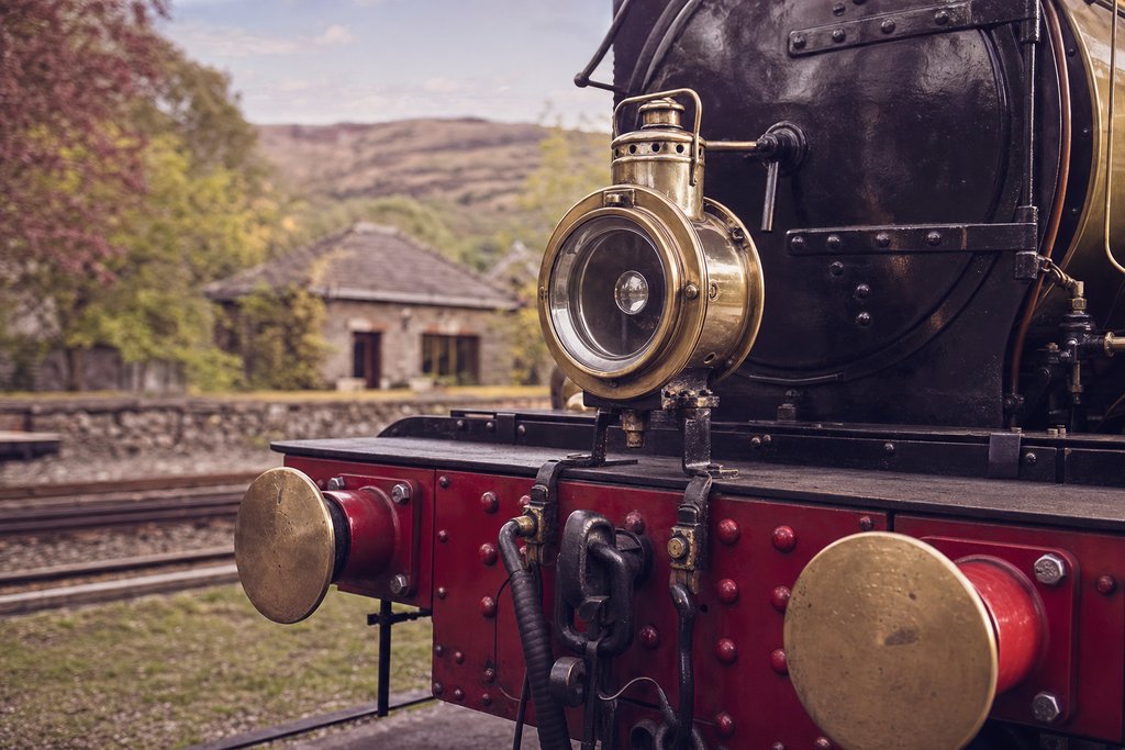 a polished brass locomotive lamp and buffer beam on a narrow-gauge engine at rest. (AI-generated image)