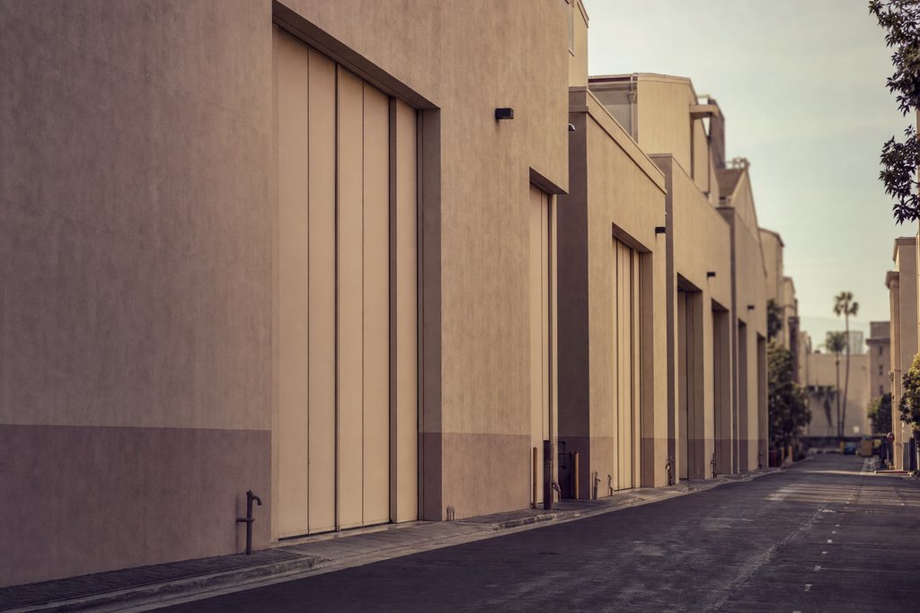 a row of tall blank warehouse doors along an empty studio service road. (AI-generated image)