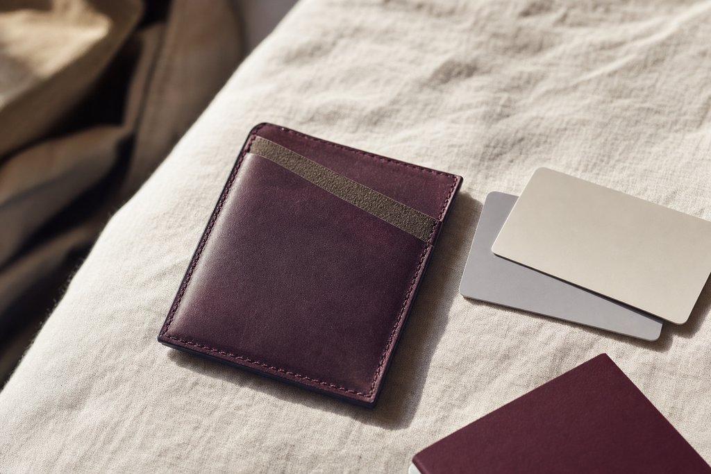a slim wallet, two plain cards and a passport corner on a pale linen surface. (AI-generated image)
