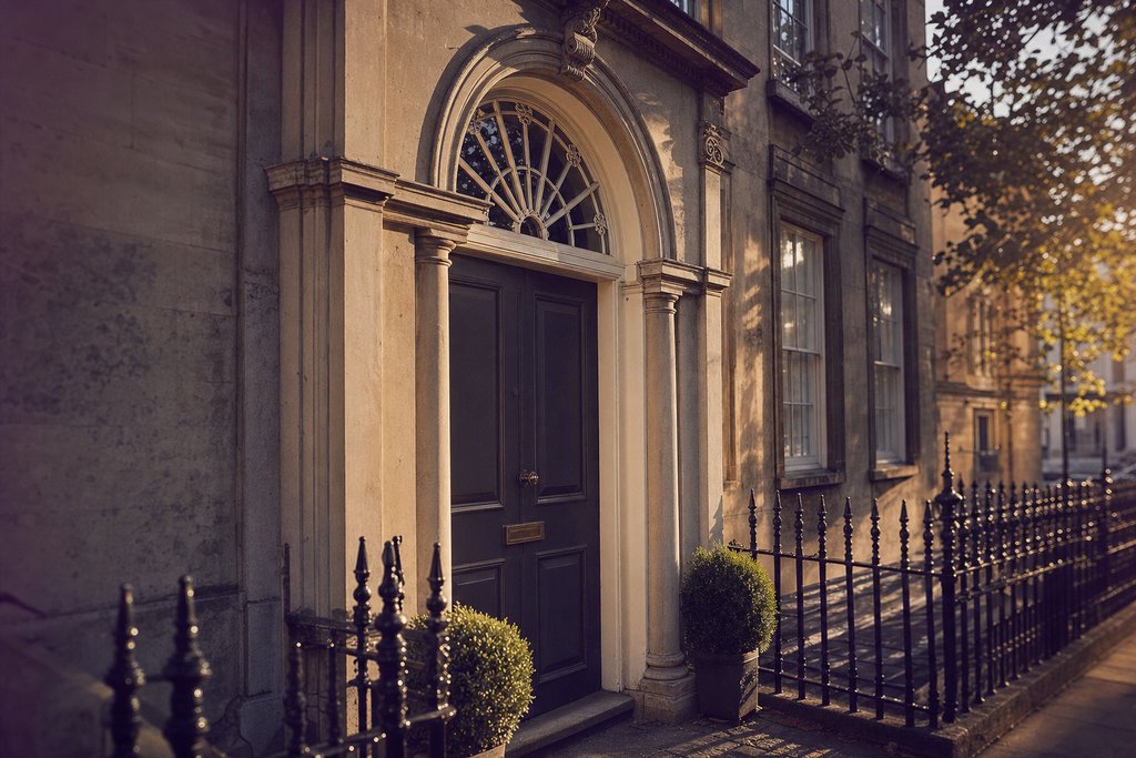 a limestone Georgian doorway with a fanlight and iron railings in low sun. (AI-generated image)