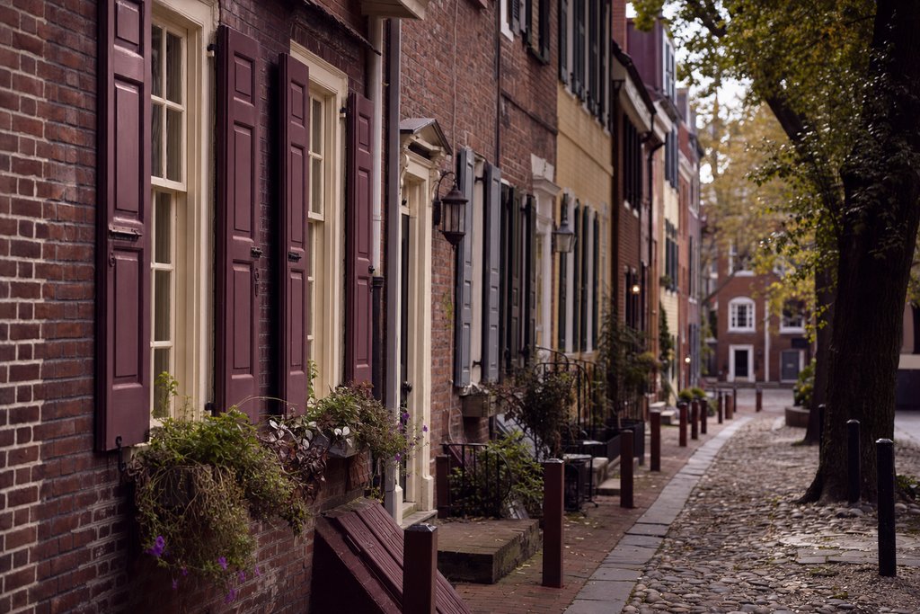 A narrow cobbled colonial alley of brick houses with painted shutters, Philadelphia. (AI-generated image)