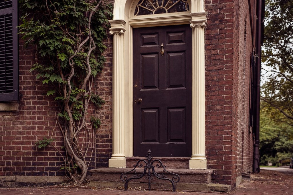 A colonial brick doorway with a fanlight and an iron bootscraper, close view. (AI-generated image)