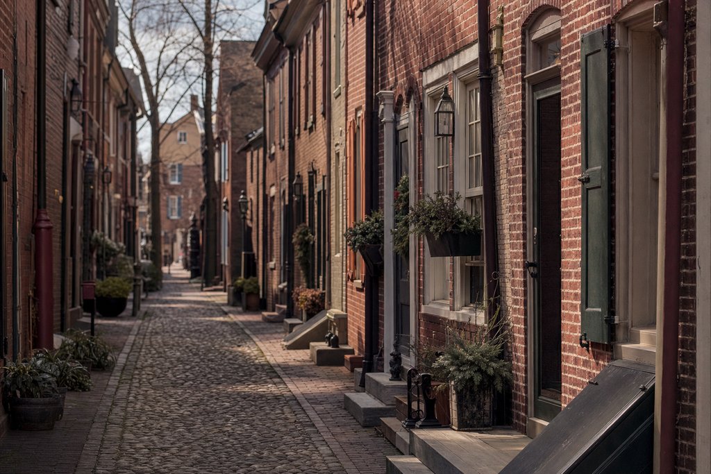 A narrow cobbled colonial alley of brick houses with painted shutters, Philadelphia. (AI-generated image)