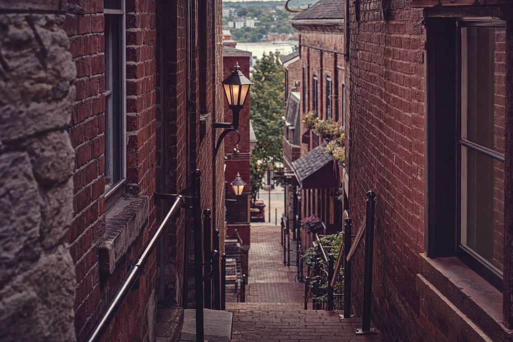 A steep brick alley staircase between market buildings with iron railings and hanging lamps. (AI-generated image)