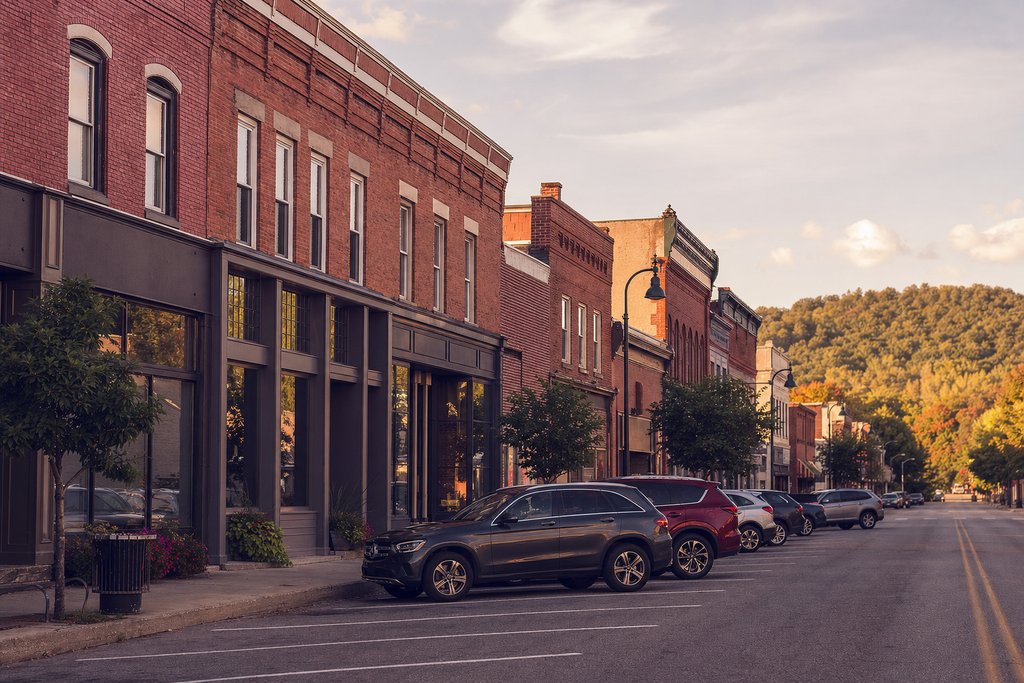 A small-town main street of red brick storefronts with angled parking in late afternoon. (AI-generated image)