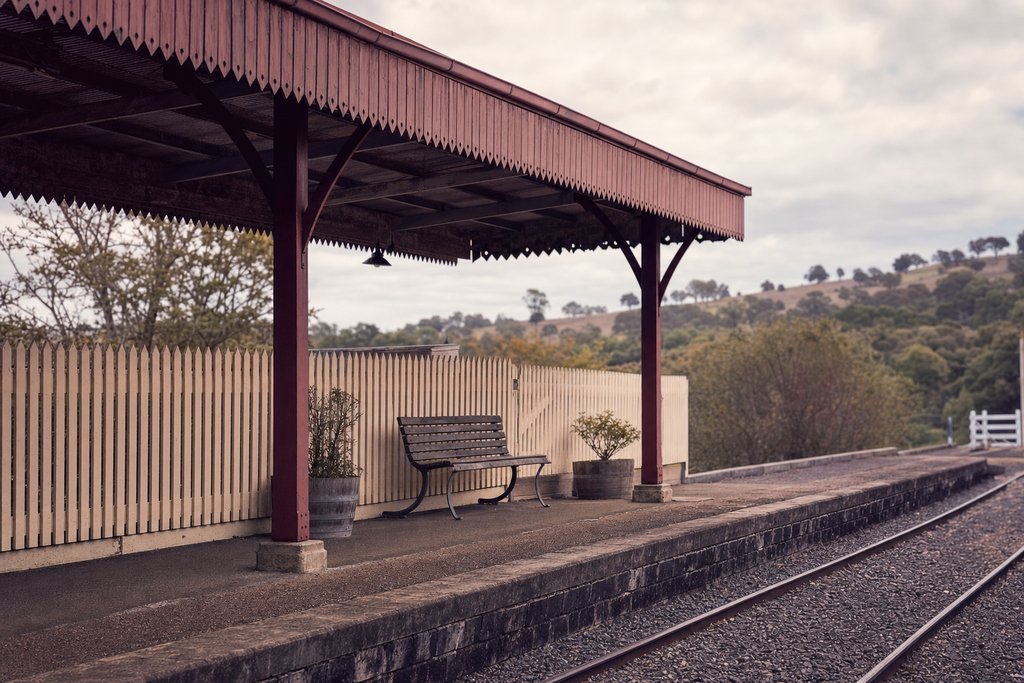A small country railway platform with a corrugated iron canopy and a picket fence. (AI-generated image)