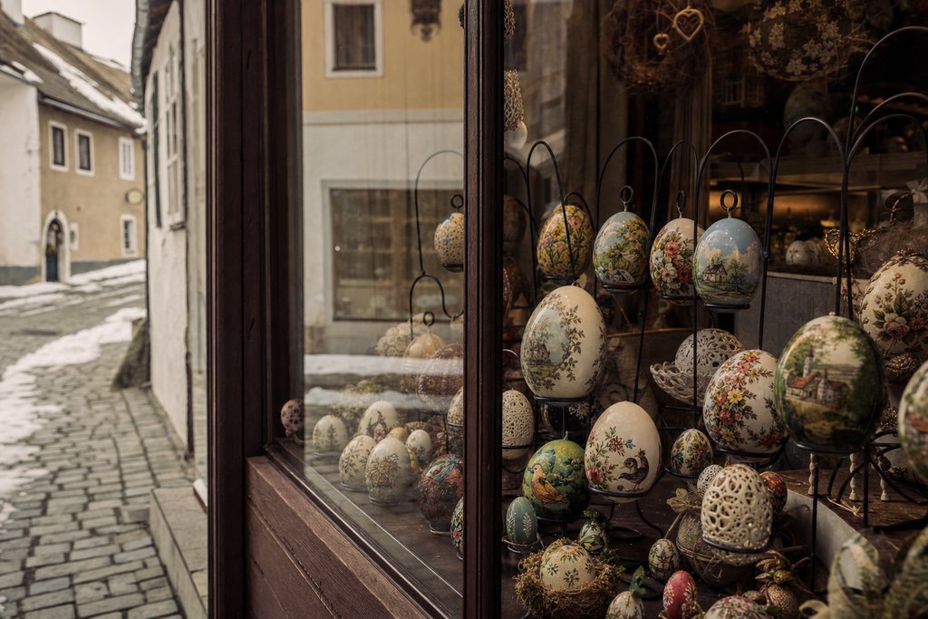A wooden Christmas market stall of hand-painted eggs and greenery with snow on its roof. (AI-generated image)