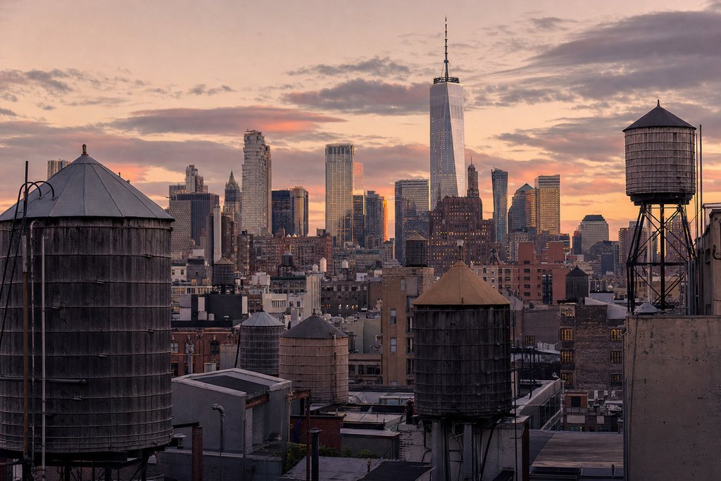 A Manhattan rooftop view across water towers toward tall towers at dusk. (AI-generated image)