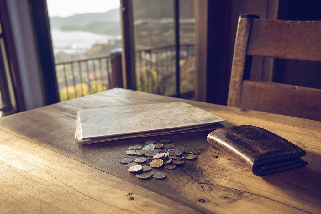 A passport, a boarding-pass stub and folded banknotes laid out on a hotel desk. (AI-generated image)